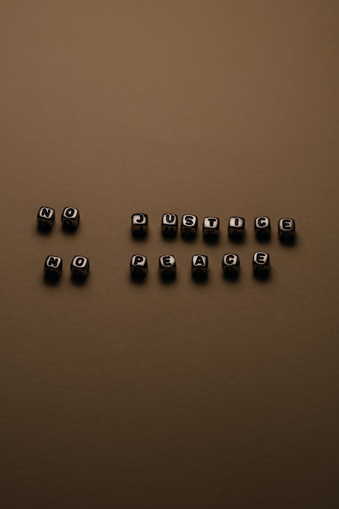 Cubes with letters spelling 'No Justice No Peace' on a brown surface, conveying a strong protest message.